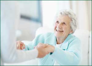 A senior woman being helped by a staff member at an assisted living facility