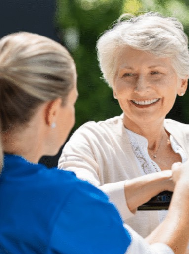 A senior woman smiling and visiting with an assisted living staff member