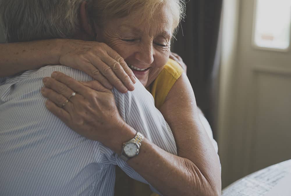 Two seniors embracing each other with a hug