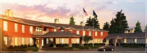 An image of The Pines Senior Living facility on a sunny day showing the font door and parking area